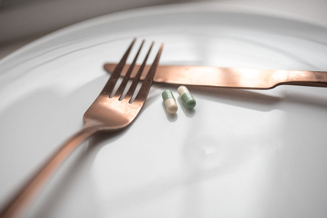 The dangers of laxative abuse in eating disorders - Pills on a an empty plate with a knife and fork