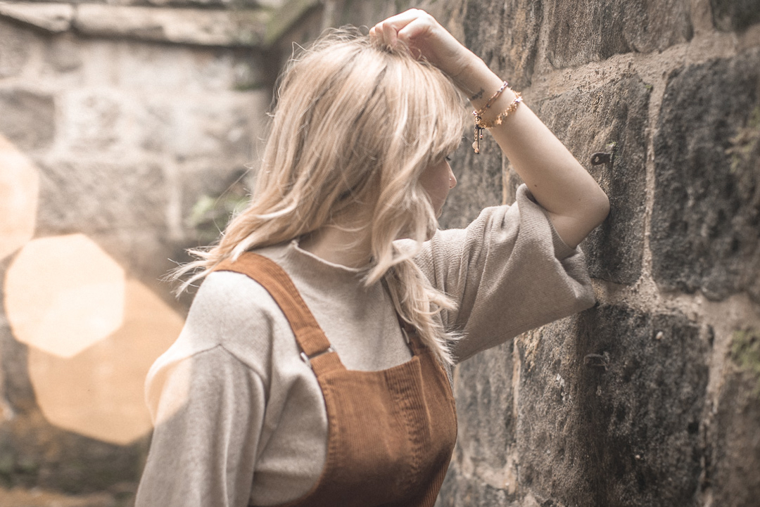 Boho Betty - Beth Anne posed against a brick wall wearing a gold star and rose gold bracelet 
