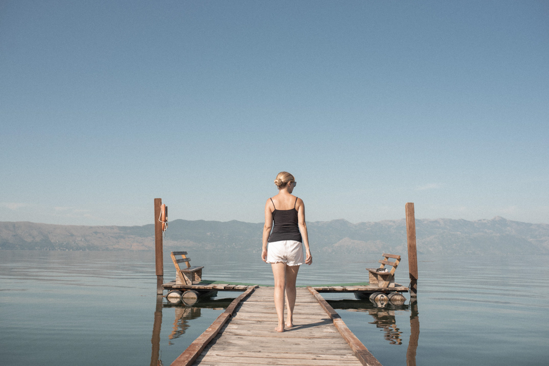 Travel around Europe - Beth walking on a jetty in Albania with mountains in the background